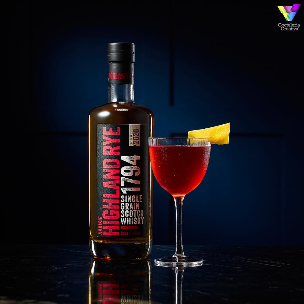 Botella de Highland Rye 1794 con copa nick y nora con cóctel decorado con twist de limón